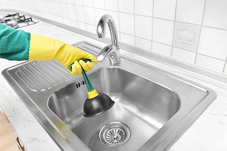 Plumber cleaning a kitchen drain